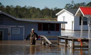 Anthony Branch carries belongings from his home as flood waters rise after Hurricane Matthew in Lumberton, North Carolina October 9, 2016. REUTERS/Chris Keane