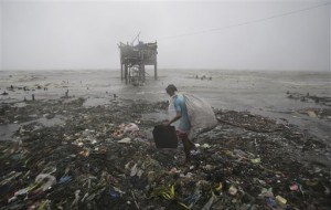 A Filipino man scavenges recyclable materials near a house on stilts stands by the bay as strong winds and rains caused by Typhoon Koppu hit the coastal town of Navotas, north of Manila, Philippines Sunday, Oct. 18, 2015. The slow-moving typhoon blew ashore with fierce wind in the northeastern Philippines early Sunday, toppling trees and knocking out power and communications. (AP Photo/Aaron Favila)