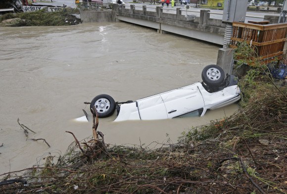A pickup truck rests against the side of Gills Creek near a bridge in Columbia, S.C., Monday, Oct. 5, 2015. Days of torrential rains kept much of South Carolina and its capital gripped by floodwaters early Monday. (AP Photo/Chuck Burton)