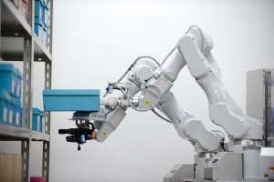 A double-arm prototype robot moves a box during a media preview hosted by Hitachi Transport System Ltd. at a warehouse in Noda City, Chiba Prefecture, Japan, on Tuesday, Aug. 25, 2015. The Japanese maker of bullet trains and power stations on Tuesday unveiled a robot that can pick up products ranging from 500-milliliter (17-ounce) plastic bottles to shoe boxes weighing around 1 kilogram (2.2 pounds). Photographer: Akio Kon/Bloomberg