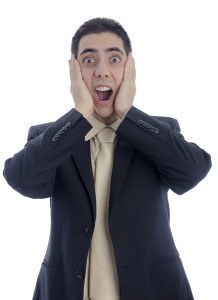 Man in business suit with his hands on his face shouting in desperation over white background.