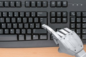 Robot hand typing on a computer keyboard.