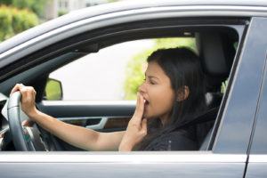 Closeup portrait tired young attractive woman with short attention span driving her car after long hours trip yawning at wheel isolated outside background. Sleep deprivation