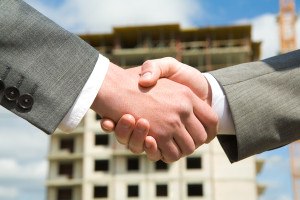 Photo of handshake of business partners after striking deal on background of building under construction