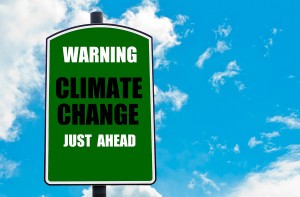 Warning Climate Change Just Ahead written on green road sign against clear blue sky background. Concept image with available copy space